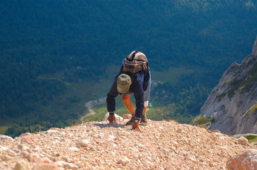 Tourist with backpack climbs on a hill