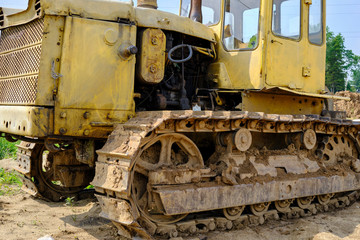 Fototapeta na wymiar An old rusty, abandoned yellow bulldozer in a field.