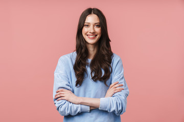 Image of attractive young woman smiling and standing with arms crossed