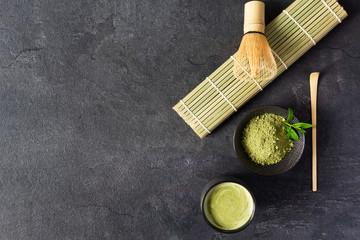 Green matcha tea drink and tea accessories on black background top view. Japanese tea ceremony...