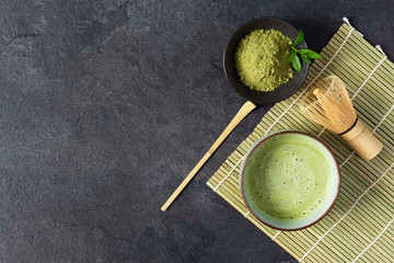 Green matcha tea drink and tea accessories on black background top view. Japanese tea ceremony concept.