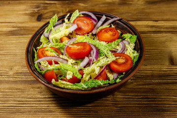 Healthy salad with savoy cabbage, cherry tomato, red onion and olive oil on wooden table