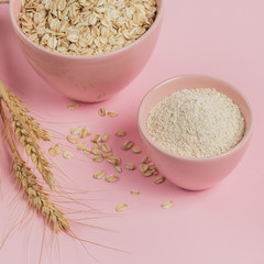 Ingredients for making homemade facial mask or scrub. Bowl of dry oat flakes with oatmeal and ears of wheat on light background