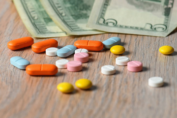 Assorted colored pills and money on the table. The concept of buying pills. The concept of increasing the price of tablets.