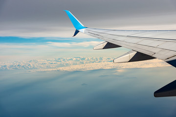 Fototapeta premium Commercial airplane flying over the clouds and the Mediterranean Sea with some islands