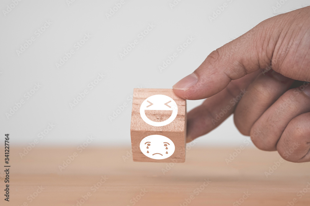 Poster customer hand flipping happy and smile face emotion which print screen on wooden block on sad emotio