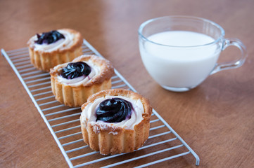 Three jam cakes and a clear mug of milk on the table, still life
