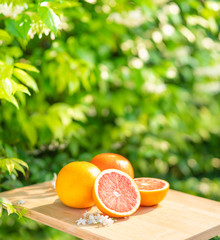 Orange fruits composition with haft and slice on wooden  plate green background
