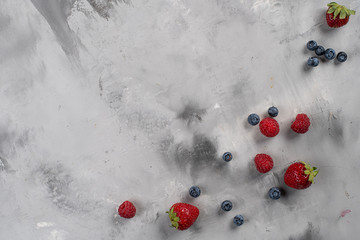 Frame of raspberries and blueberries. Flat lay composition. Gray concrete background. Top view. Copy space.