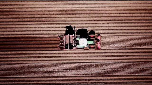 Bauer f&auml;hrt mit Traktor &uuml;ber Feld und pflanzt Kartoffeln an