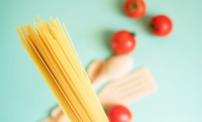 Spaghetti on a light background with tomatoes, wood spoon.