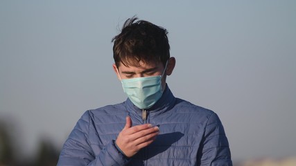 A man in a medical mask coughs. An isolated guy is sick. Coronavirus, epidemic 2020.