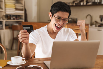 Image of asian man holding credit card and making winner gesture