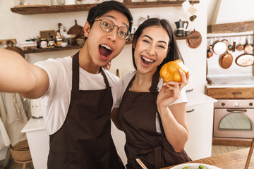 Image of excited couple taking selfie on smartphone and smiling