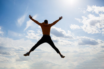 Fototapeta premium guy tourist freelancer on a background of blue sky with white clouds, bright sunny day, nature and human freedom