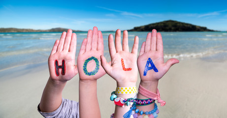 Kids Hands Holding Colorful Spanish Word Hola Means Hello. Ocean And Beach As Background © Nelos