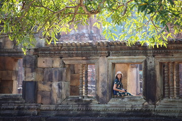 The woman is at the window of the Prasat Mueang Tam (Mueang Tam castle) in Buriram, Thailand