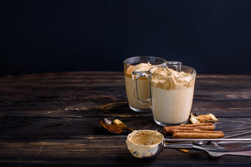 Delicious and fragrant dalgona coffee in glass cups, cinnamon sticks, dried mushrooms, a spoon of instant coffee, sugar.