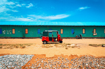 Trójkołowiec tuk-tuk na plaży, wśród suszonych ryb i niebieskiego nieba. © insomniafoto