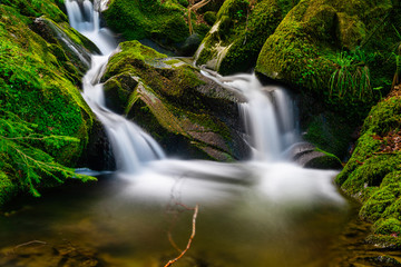 Long time exposure of a small waterfall with cascades in the heart of the Black Forest with beautiful color mood in spring