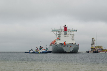 LNG TERMINAL AND GAS TANKER - A large ship maneuvers into the unloading quay
