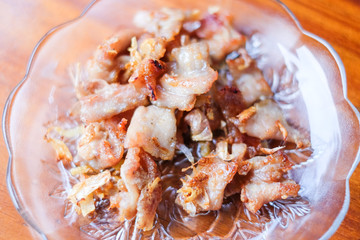 The garlic fried pork serve on white dish set on brown table - homemade food concept.