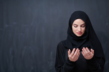 muslim woman making traditional prayer to God in front of black chalkboard