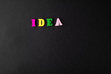 The word idea is written from multicolored wooden letters on a black background.
