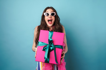 Photo of delighted young woman in sunglasses posing with gift box