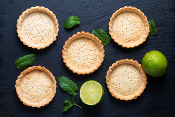Food concept Homemade emty pie crust for organic Lemon, lime tarts or mini pie on black slate stone board