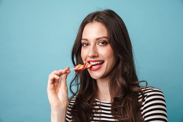 Photo of joyful beautiful woman smiling and eating lollipop