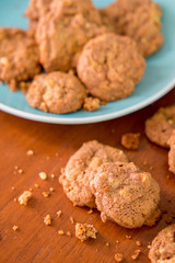 Delicious crunchy homemade chocolate cookies with walnut chunk on top of wooden table and white background.