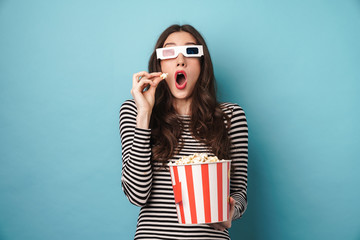 Photo of shocked young woman eating popcorn while watching movie