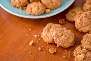 Delicious crunchy homemade chocolate cookies with walnut chunk on top of wooden table and white background.