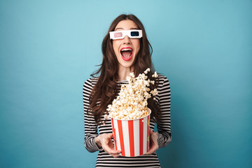 Photo of excited young woman eating popcorn while watching movie - obrazy, fototapety, plakaty