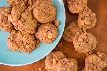 Delicious crunchy homemade chocolate cookies with walnut chunk on top of wooden table and white background.