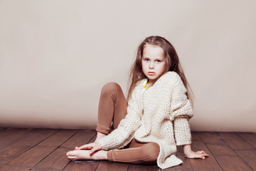 little girl sitting on the floor and sad