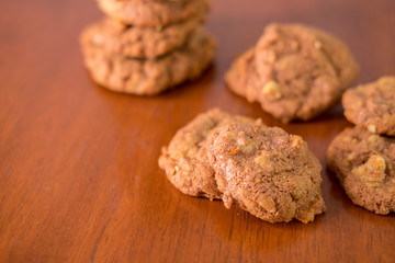 Delicious crunchy homemade chocolate cookies with walnut chunk on top of wooden table and white background.
