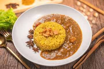 Curry chicken with yellow rice on plate over wooden background, Chicken with basmati rice