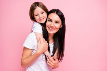 Photo of pretty young mommy hold arms hugging little daughter good mood lovely sincere cardiac feelings piggyback wear casual t-shirts jeans isolated pastel pink color background - obrazy, fototapety, plakaty