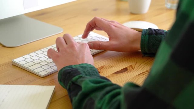 Close up image of man typing at keyboard during the day.