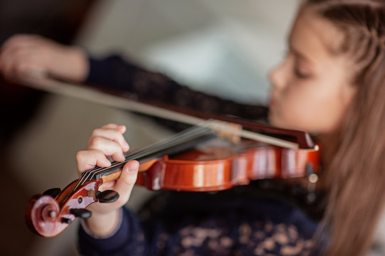 Home lesson for a girl playing the violin. The idea of activities for children during quarantine. Music concept