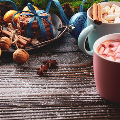 Christmas background of two mugs of hot chocolate with marshmallows, spruce branch and tray with gingerbread cookies on wooden table