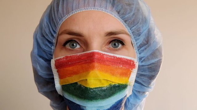 Portrait of a doctor in a mask, on which a rainbow is drawn as a sign of hope of victory over a coronovirus infection.