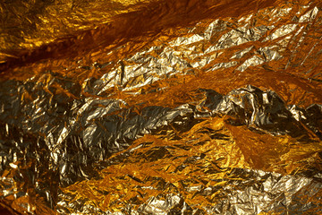 Texture of a thin crumpled sheet of foil. Crumpled foil background. Stock photo foil. Gold chrome...