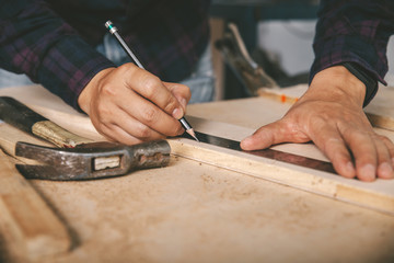 carpenter with a pencil and ruler mark on wooden board on table. Construction industry, housework do it yourself.