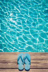 Flip-flops on wooden background near swimming pool