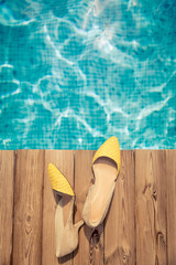 Woman's shoes on wooden background near swimming pool