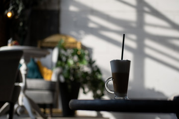 Delicious latte on the table in the decorated room. Hot coffee drink with milk in a glass goblet.