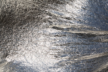 Texture of a thin crumpled sheet of foil. Crumpled foil background. Stock photo foil. Silver chrome...